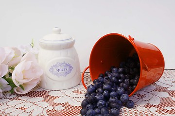 Image showing Blueberries spilling out of a red pail