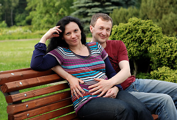 Image showing Young happy couple (pregnant woman) on bench