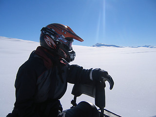 Image showing Man with helmet on snow scooter