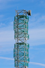 Image showing Telecommunications mast set against blue sky and small clouds