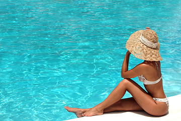 Image showing Woman in hat relaxing beside the pool
