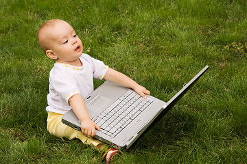 Image showing Little child playing with notebook on the grass