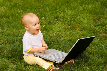 Image showing Little child playing with notebook on the grass