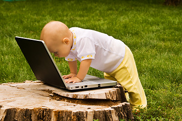 Image showing Little child playing with notebook on the grass