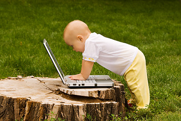 Image showing Little child playing with notebook on the grass