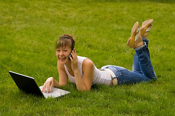 Image showing Happy young woman with notebook and mobile phone on the grass