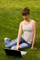 Image showing Young woman with notebook on the grass