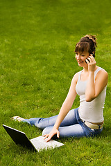 Image showing Happy young woman with notebook and mobile phone on the grass