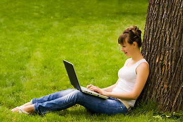 Image showing Young woman on the grass with notebook