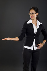 Image showing attractive businesswoman presenting something over black background