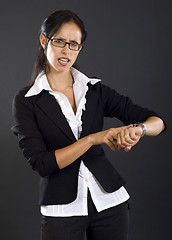 Image showing attractive businesswoman checking time over black background