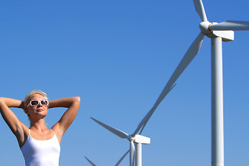 Image showing young woman dreams about the future on a wind farm beneath eolic