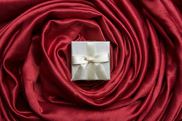 Image showing White gift box on red silk