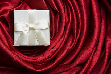 Image showing White gift box on red silk