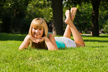 Image showing Young smiling girl lies on grass