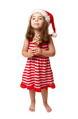 Image showing Little girl wearing santa hat and holding Christmas candy