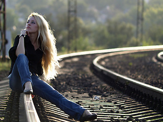 Image showing Young woman sitting on rail