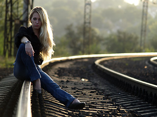 Image showing Young woman sitting on rail