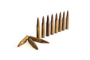 Image showing Row of standing  M16 cartridges with some fallen isolated