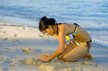 Image showing beautiful young woman playing with the sand