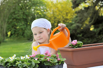 Image showing Young girl watering flowers