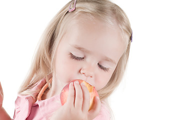 Image showing Little girl eating peach in studio