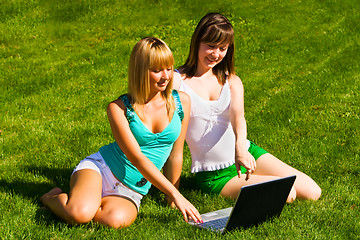 Image showing Two young girls on the grass with notebook