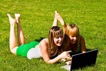 Image showing Two young girls on the grass with notebook