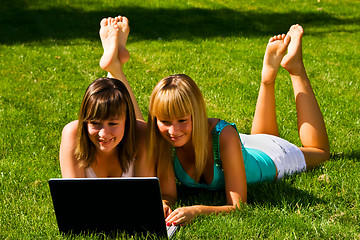 Image showing Two young girls on the grass with notebook