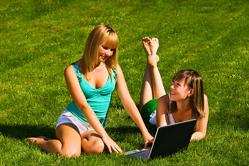 Image showing Two young girls on the grass with notebook