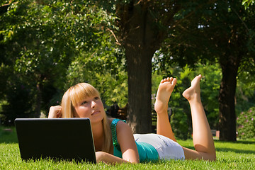 Image showing Young thoughtful girl on the grass with notebook looks at the sky