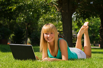 Image showing Young smiling girl on the grass with notebook