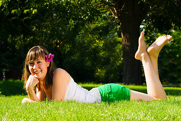 Image showing Young smiling girl lies on grass