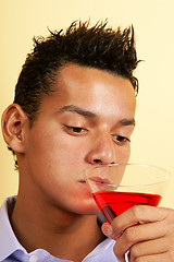 Image showing Young man drinking red cocktail