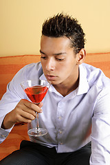 Image showing Young man drinking red cocktail