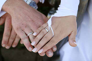 Image showing Three hands and only two rings.