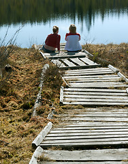 Image showing Two girls sit on pier