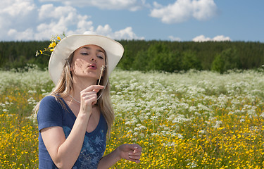 Image showing Beautiful girl blows on dandelion in white hat