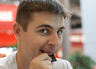 Image showing Young man eats chocolate