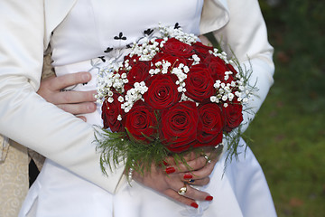 Image showing Bride and groom holding hands, bride holding bouquet