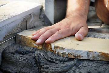 Image showing Worker hand on flagstone