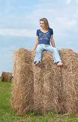 Image showing Beautiful girl sits on hay