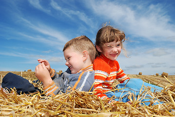 Image showing smiling boy and girl in straw outdoors