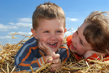 Image showing smiling boy and girl in straw outdoors close-up