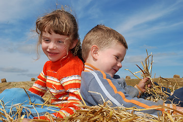 Image showing Two smiling children in straw outdoors