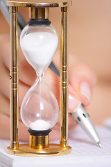 Image showing Female hand with pen and sand clock