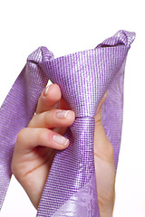 Image showing Female hand holding a violet tie with the fastened knot