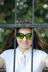 Image showing The young woman in sun glasses behind an iron protection