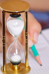 Image showing Sand-glass with female hand holding pencil