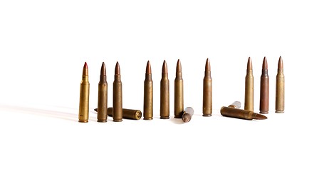 Image showing Row of standing  M16 cartridges with some fallen isolated